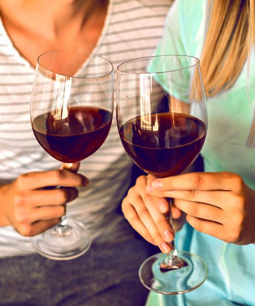 Close up details of romantic evening of pretty couple drinking red wine end enjoying time together, modern interior and trendy elegant clothes.
